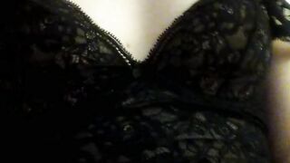 Home striptease in black lace lingerie and showing beautiful naked breasts. Close-up