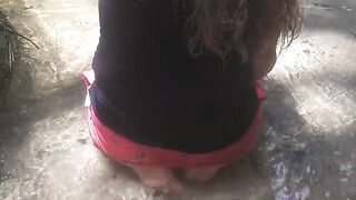 Cute long hair girl on her knees looking for shells to collect in popular spring creek