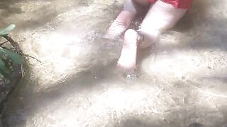 Cute long hair girl on her knees looking for shells to collect in popular spring creek