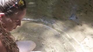 Cute long hair girl on her knees looking for shells to collect in popular spring creek