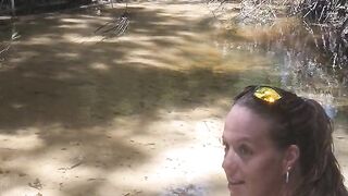 Cute long hair girl on her knees looking for shells to collect in popular spring creek