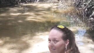 Cute long hair girl on her knees looking for shells to collect in popular spring creek