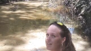 Cute long hair girl on her knees looking for shells to collect in popular spring creek