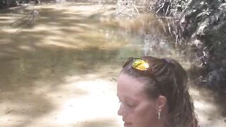 Cute long hair girl on her knees looking for shells to collect in popular spring creek