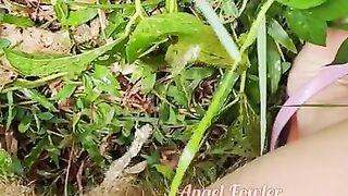 Village woman in a red tunic is pissing in the middle of a green field