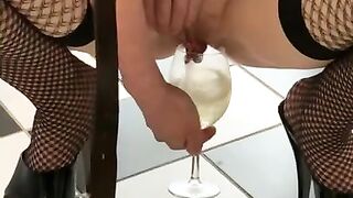 Dirty slut in plaid skirt and stripper heels fills a glass with piss